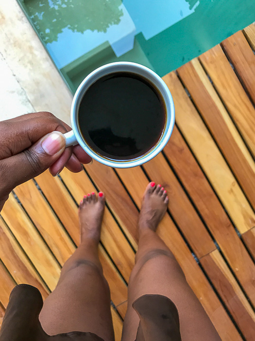 holding mug of black coffee on pool deck