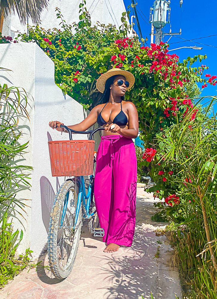 Jazzmine walking alongside bike underneath half arc of pink flowers