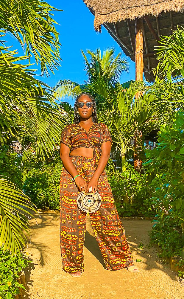 Jazzmine holding small wooden handbag surrounded by palm trees