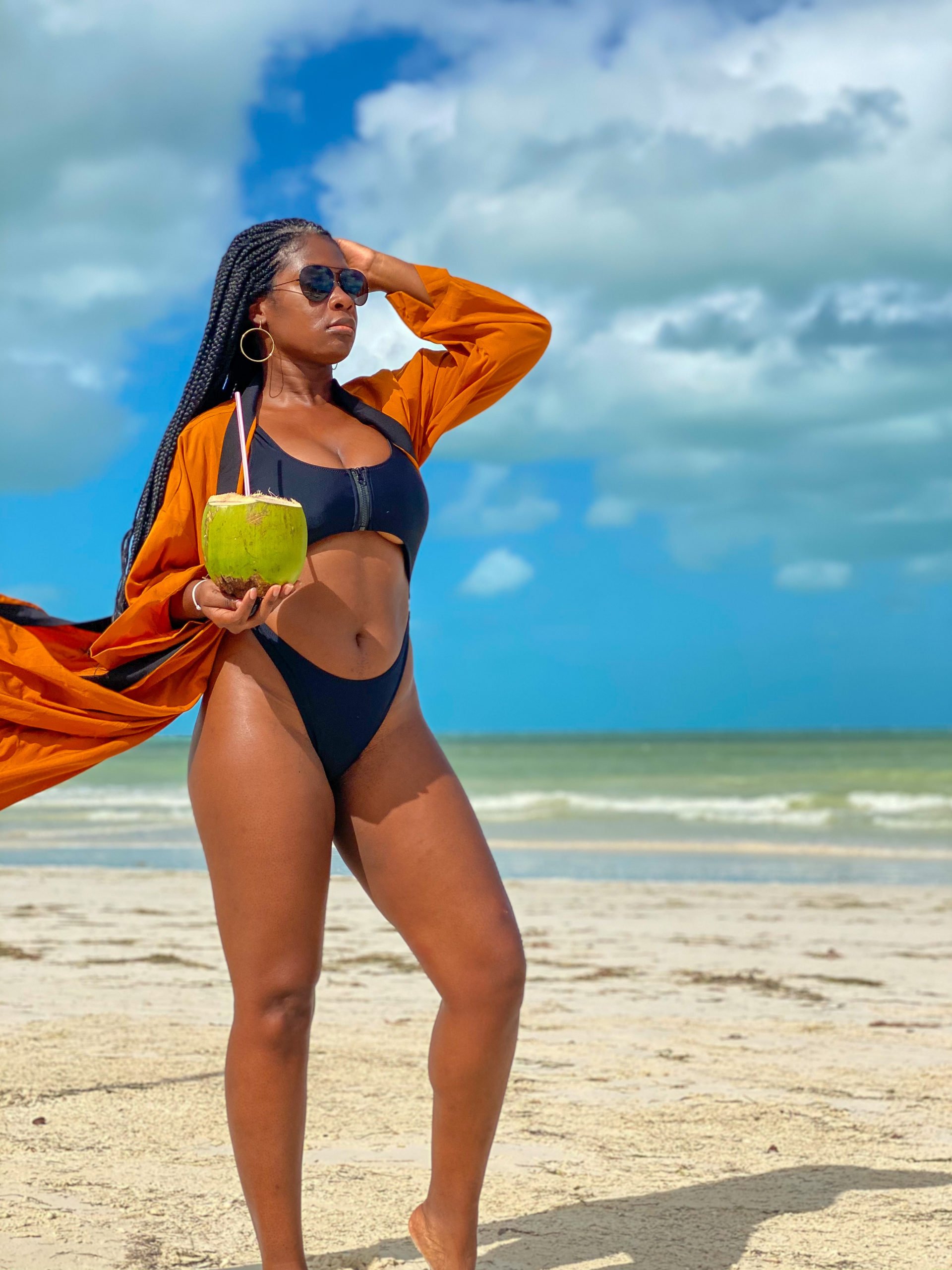 Jazzmine standing on beach holding fresh coconut and straw