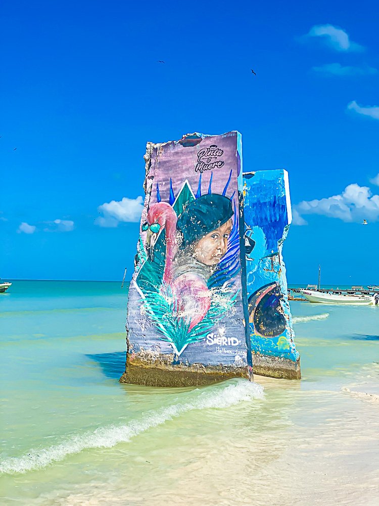 murals painted on large stones at beach shoreline