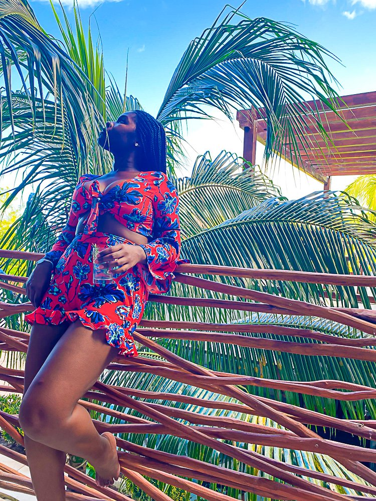 Jazzmine leaning on outdoor balcony flanked by palm trees