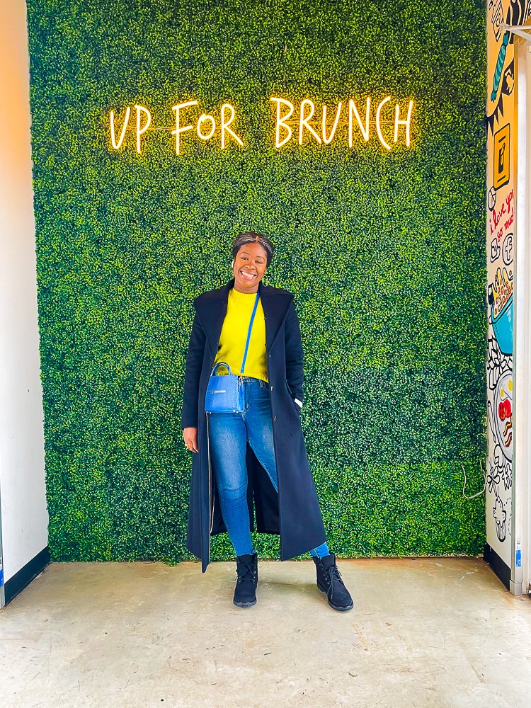 Jazzmine posing under Up for Brunch neon sign.