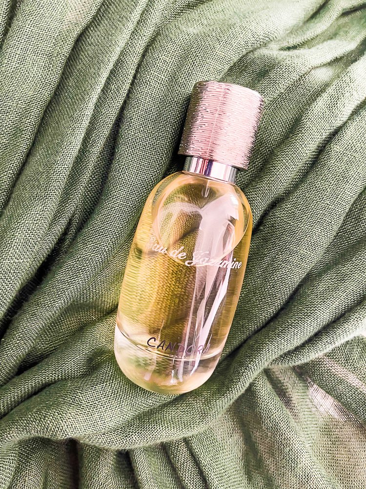 bottle of French perfume laying on top of green fabric.