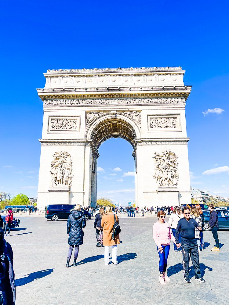 People taking photos in front of Arc de Triomphe monument in France.