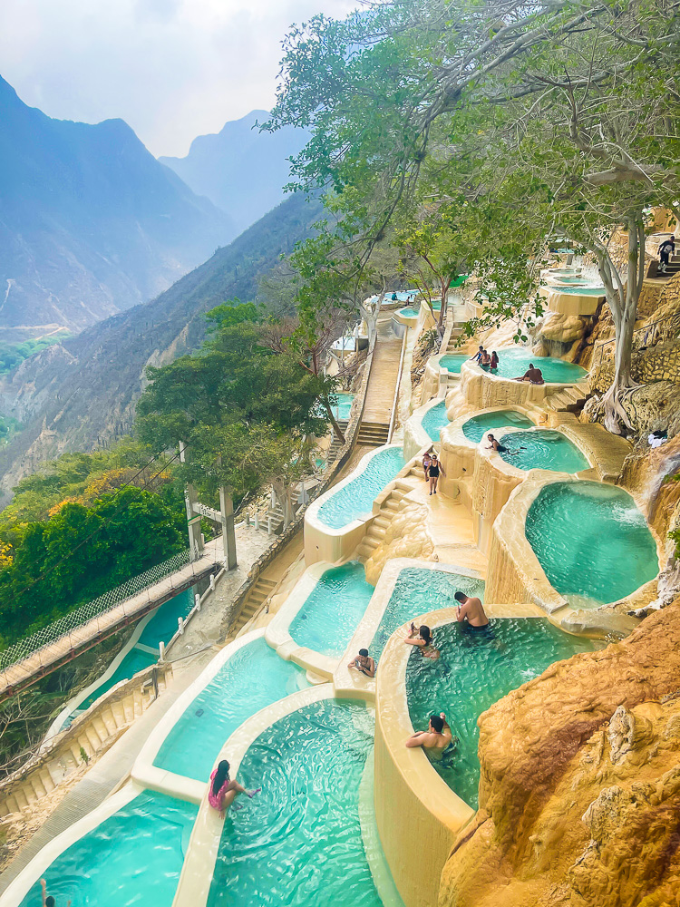 visitors lounging in naturally blue warm thermal limestone pools at Las Grutas de Tolantongo park and resort on sunny spring day.