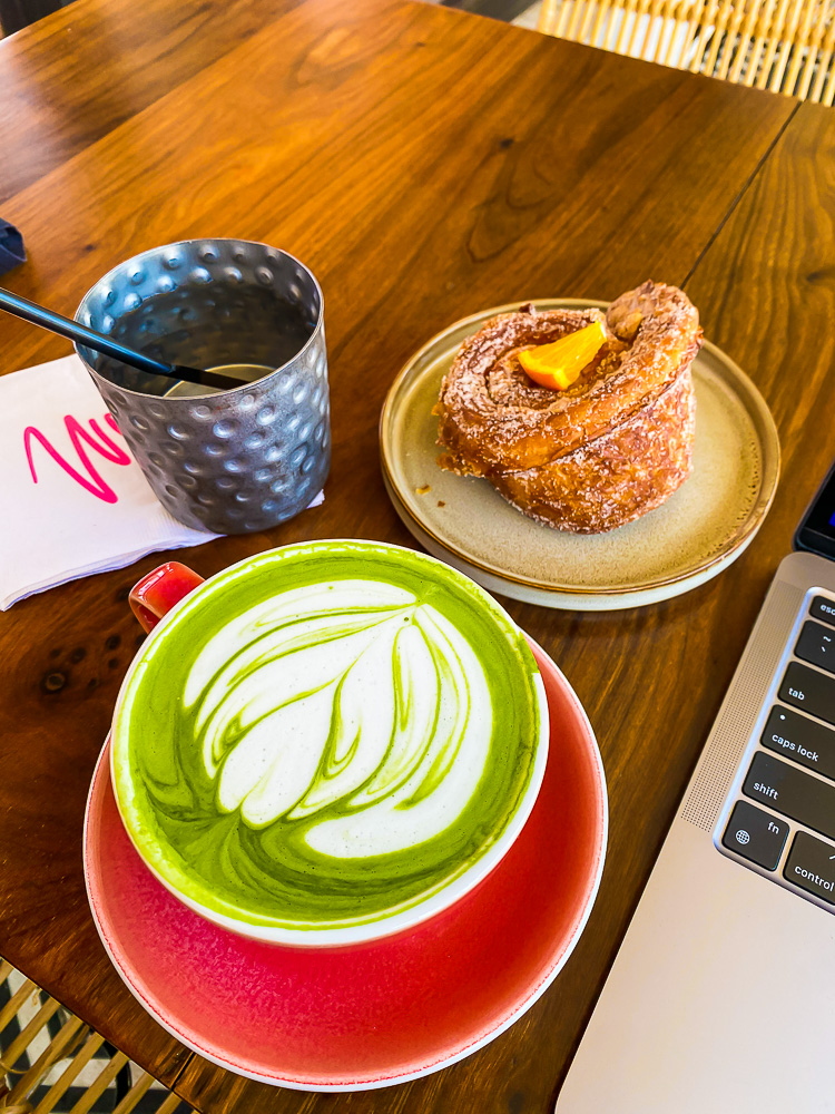 matcha latte and morning bun next to laptop on table at Wild Montrose Houston.