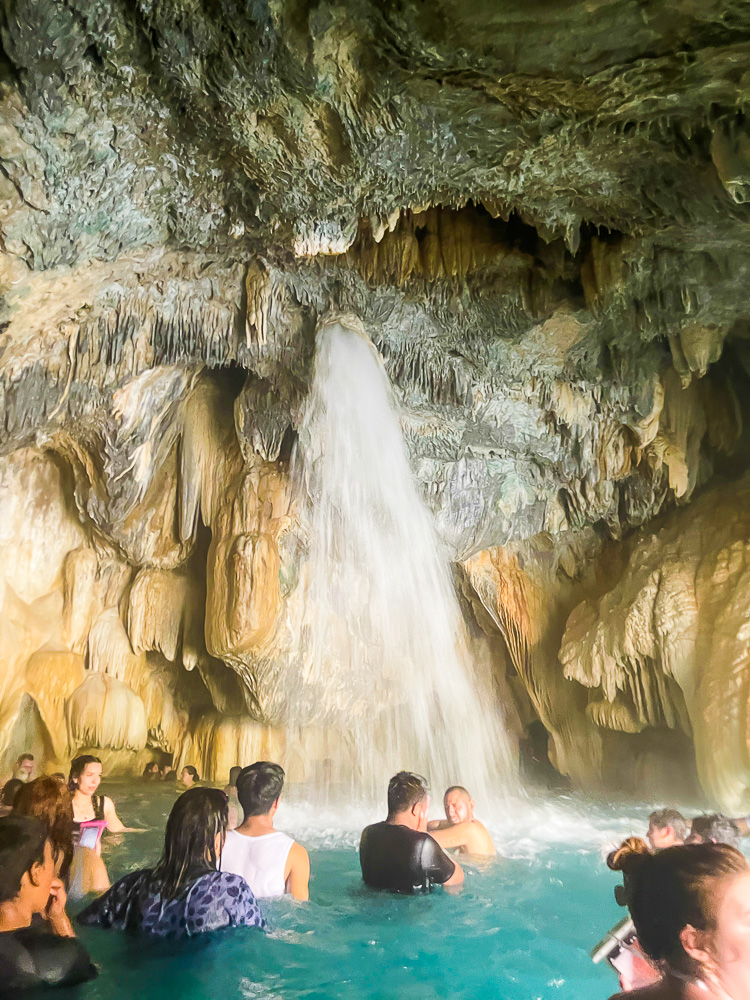water spraying down over swimmers inside Tolantongo cave.