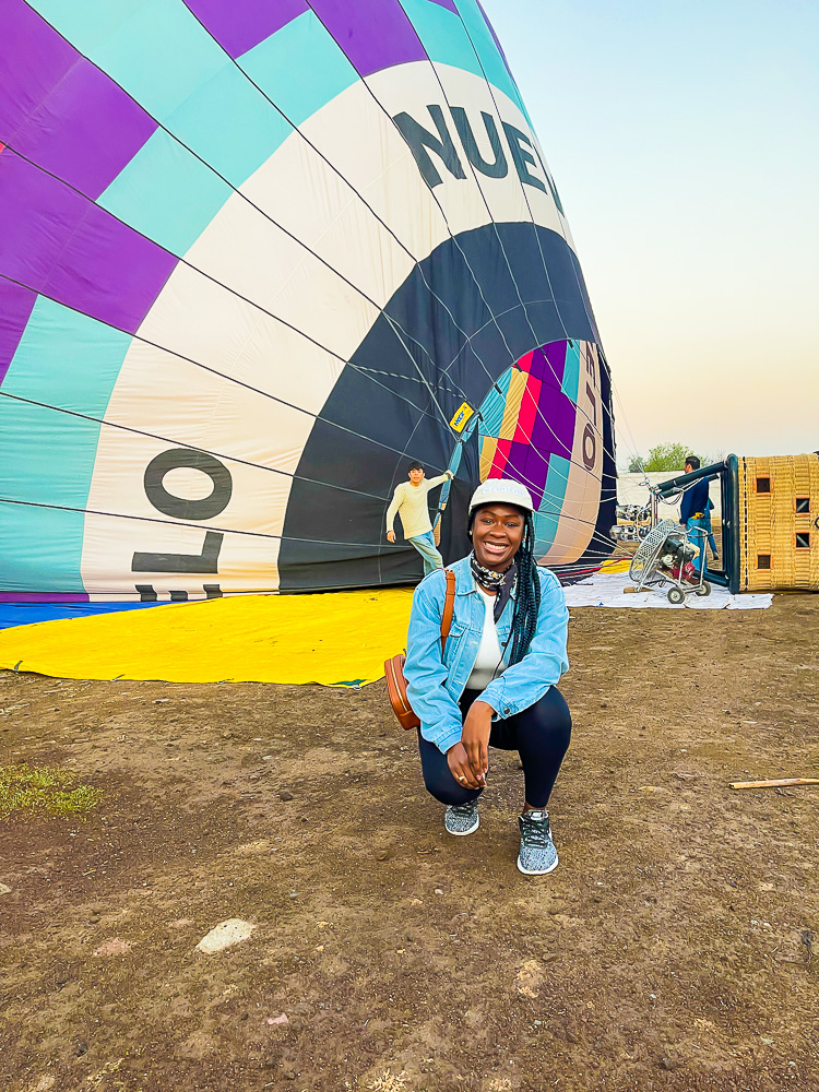 Jazzmine kneeling in front of a Teotihuacan hot air balloon as it's being inflated for takeoff. 