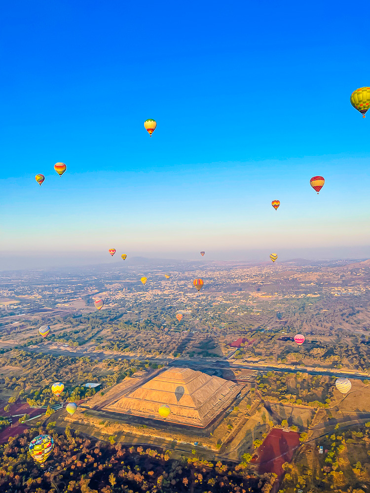colorful hot air balloons soaring above a Teotihuacan pyramid and the archaeological zone.