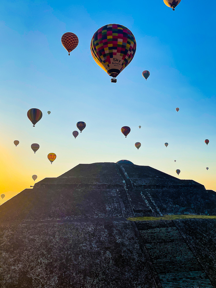 watching hot air balloon experience fly above the Mexican Teotihuacan pyramids as the mornin sun comes up.