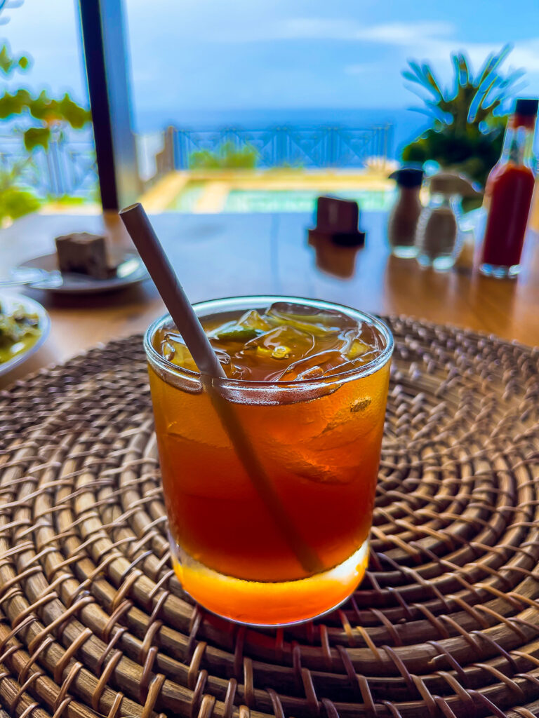 orange-colored rum punch in a rocks glass over ice with a paper straw.