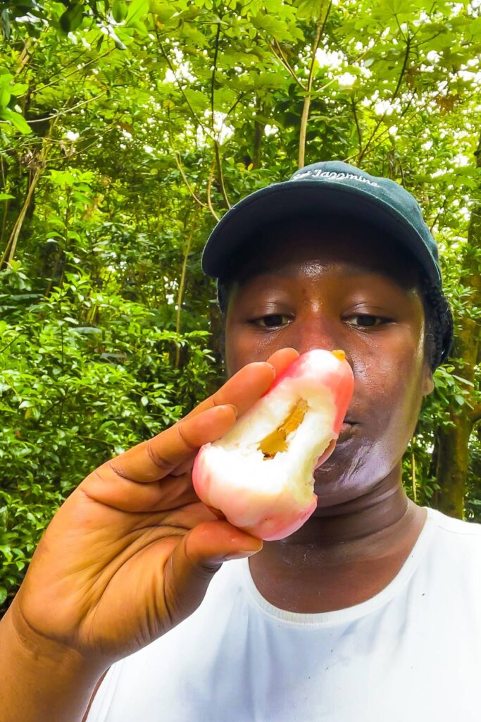 Jazzmine holding half-eaten local apple in Dominica rainforest.