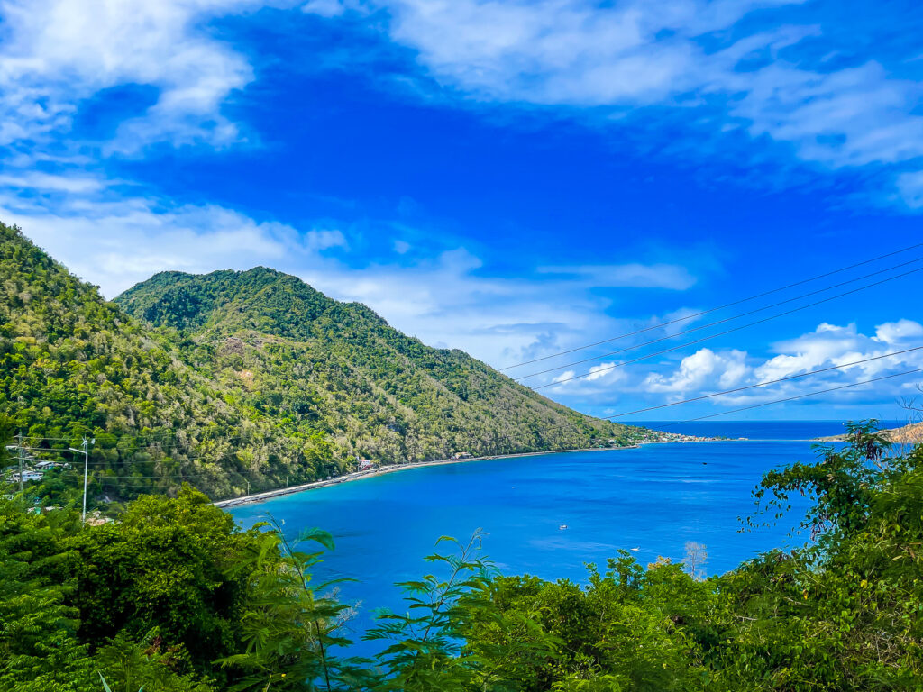 deep blue waters of Soufriere Bay flowing out into the Caribbean Sea flanked by green mountains.
