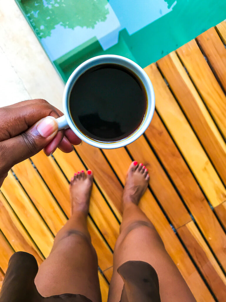 brown hand holding mug of espresso on private pool patio at Amaka Calma Riviera Tulum.