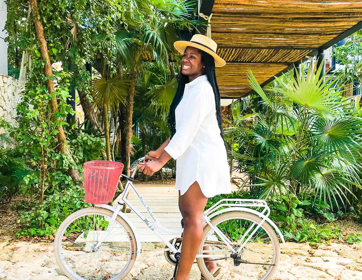 Jazzmine wearing a crisp white collared beach cover-up and straw boater hat in Tulum.