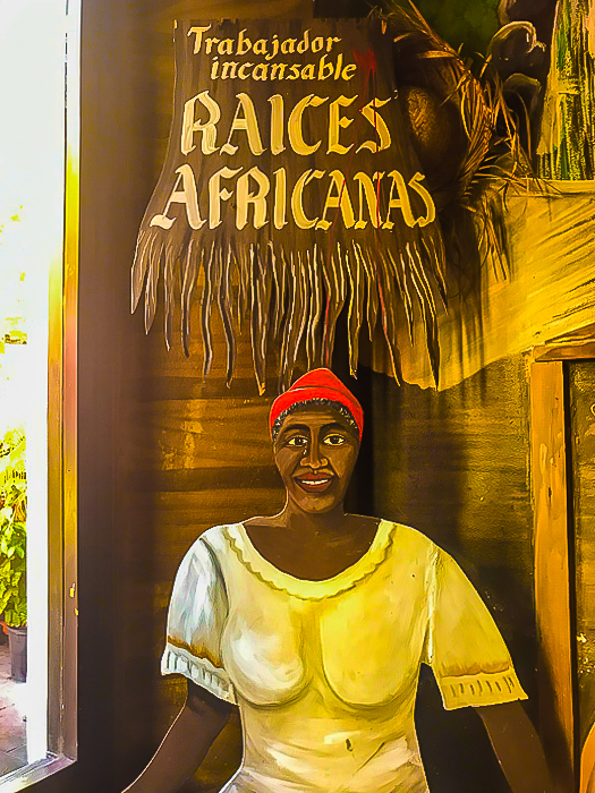 painted sign reading "trabajador incansable Raices Africanas" on wall at Raices Restaurant in Puerto Rico.