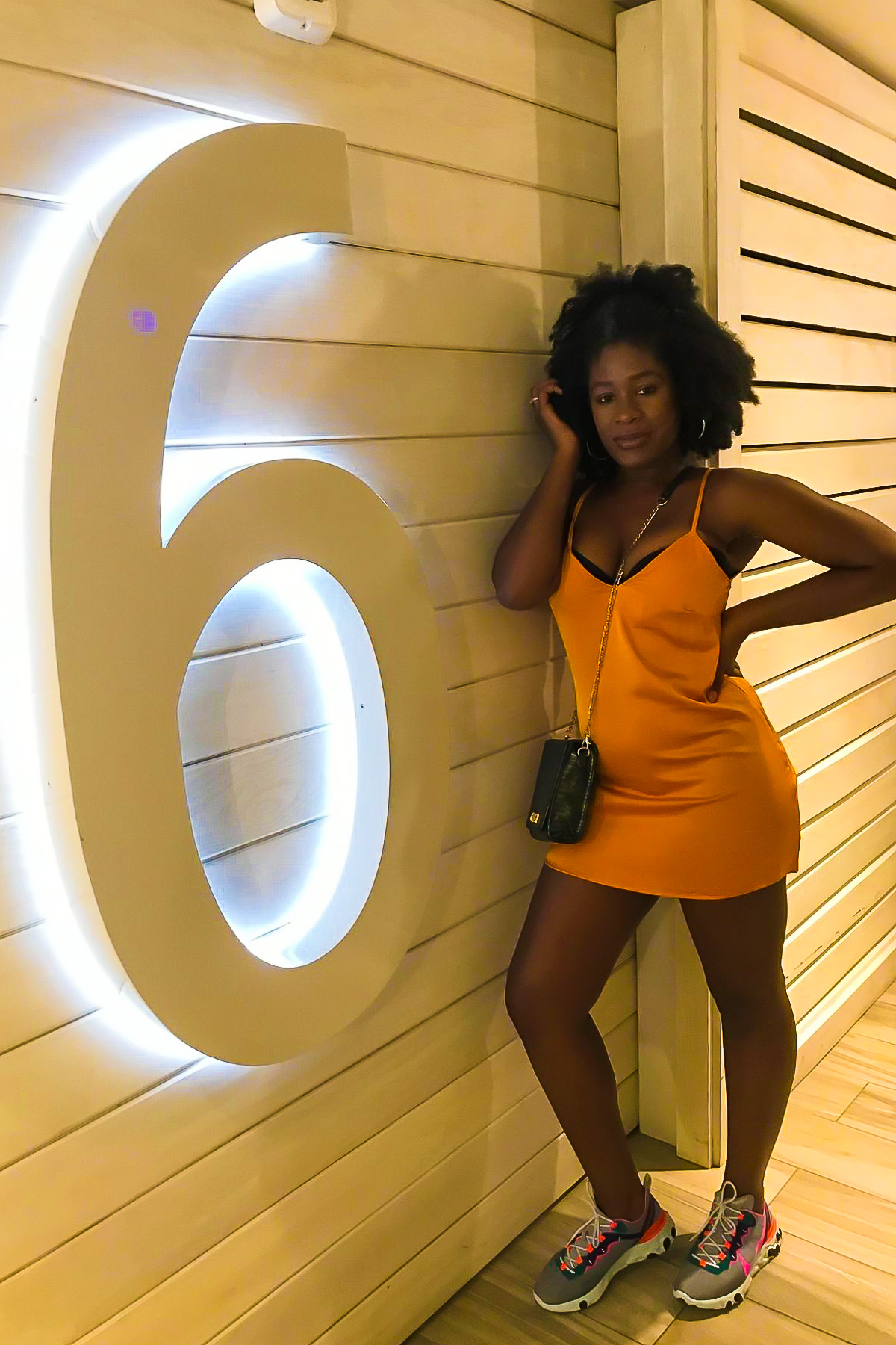 Jazzmine wearing a marigold colored mini silk slip dress and colorful sneakers to go out at night. in San Juan Puerto Rico.