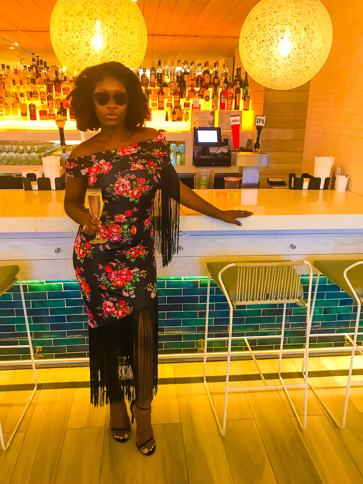Jazzmine wearing floral off the shoulder dress with long black fringe with black high heel sandals and black sunglasses for a salsa dancing class in San Juan, Puerto Rico.