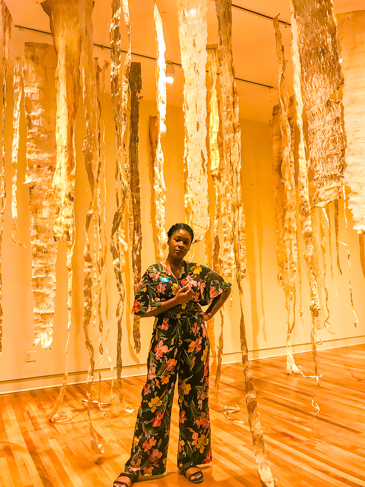 Jazzmine posing in an exhibit room at Honolulu Museum of Art. wearing. a hibiscus-printed co-ordinating pants set.