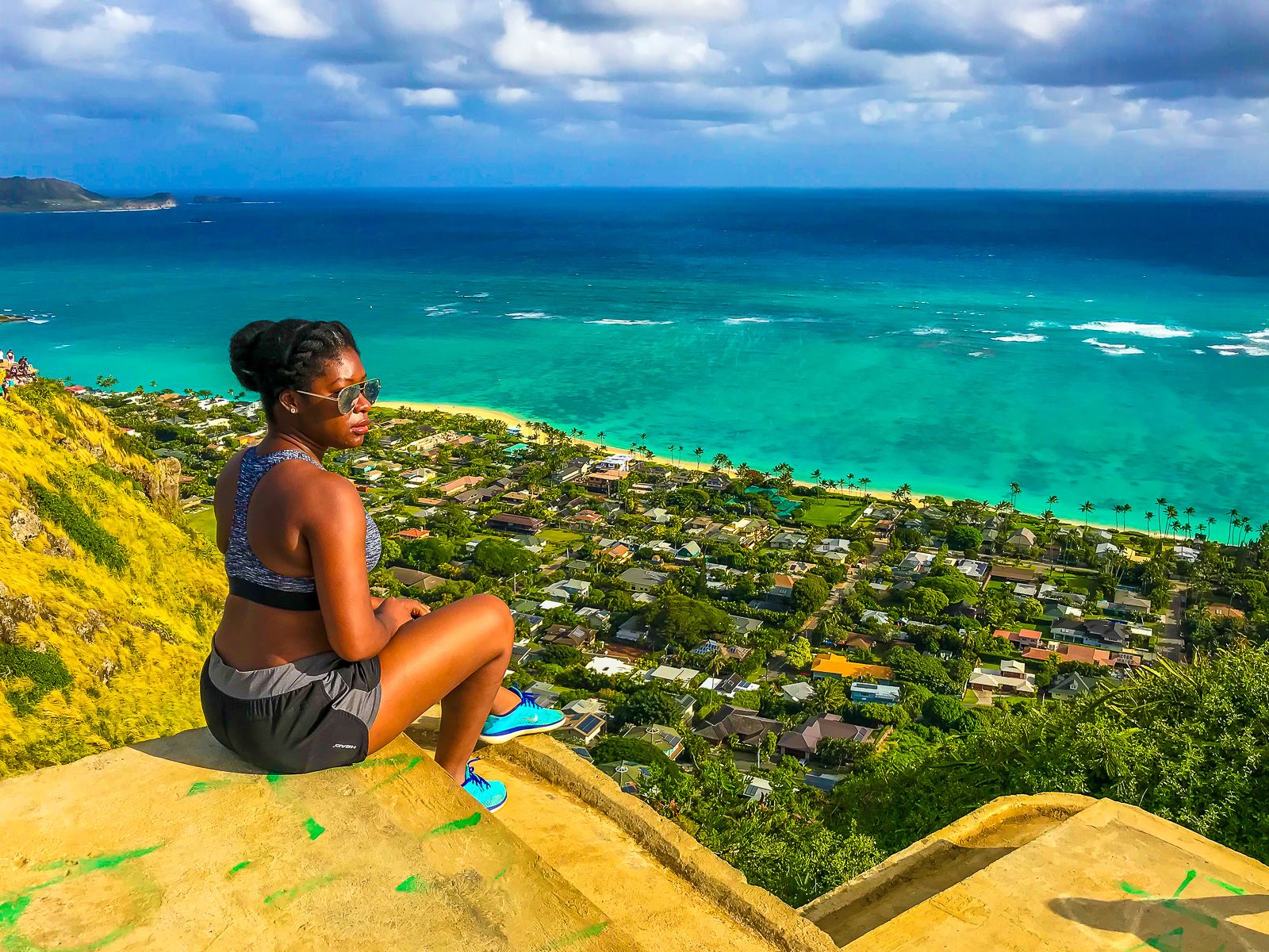 Jazzmine sitting on a platform along the Lanikai Pillbox hike overlooking Lanikai Beach during a solo trip to Oahu, Hawaii.