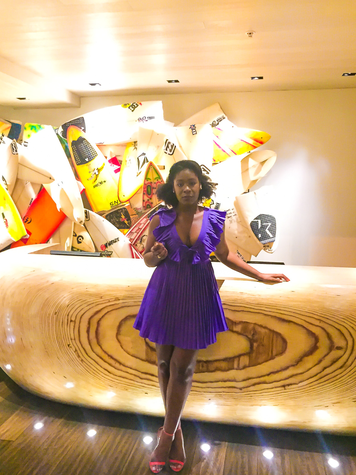 Jazzmine in the Modern Honolulu lobby wearing a pleated purple mini dress and salmon-colored high-heeled sandals.