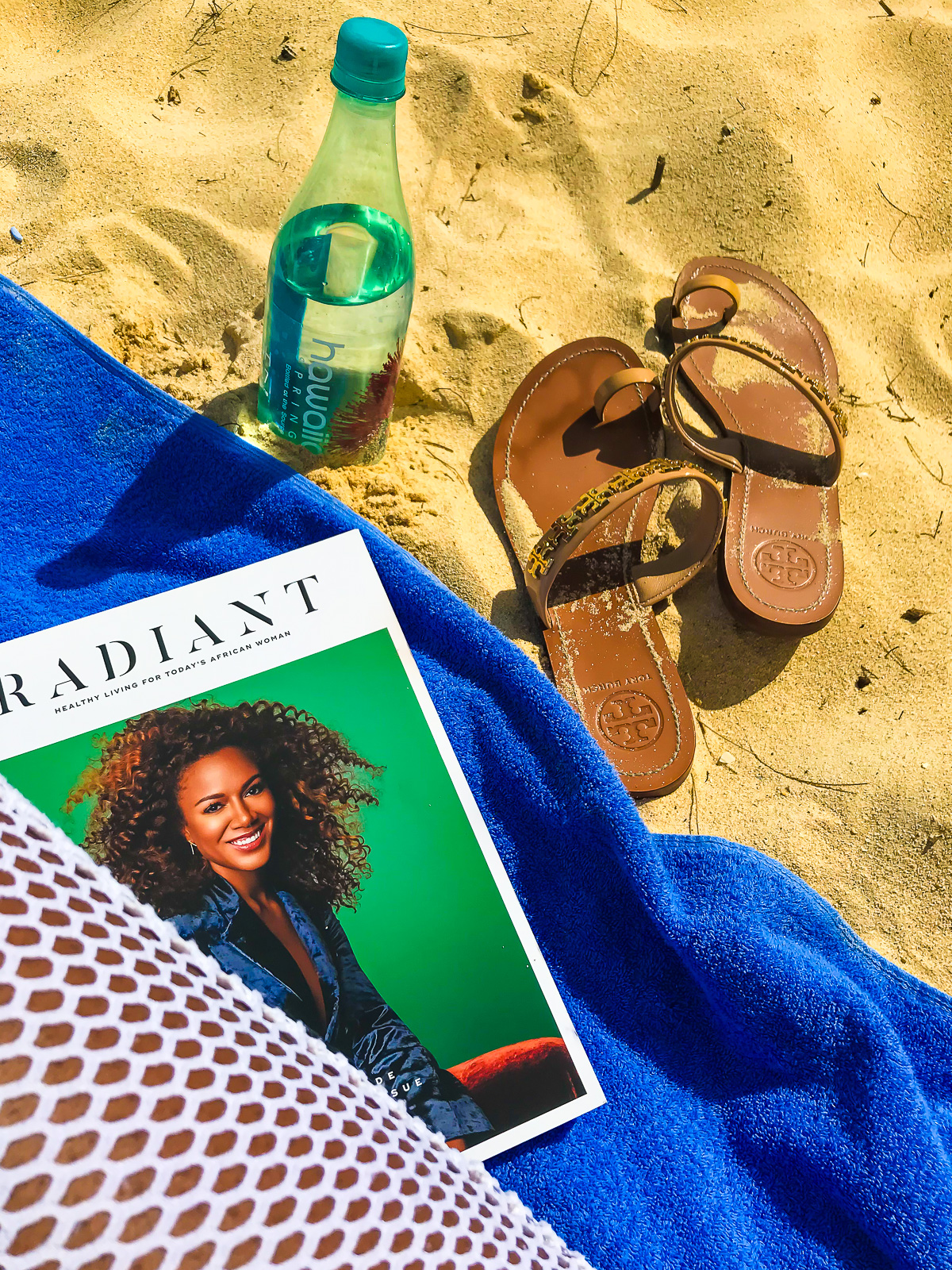 magazine, sandals, and water bottle in the sand at Waimanalo Beach.