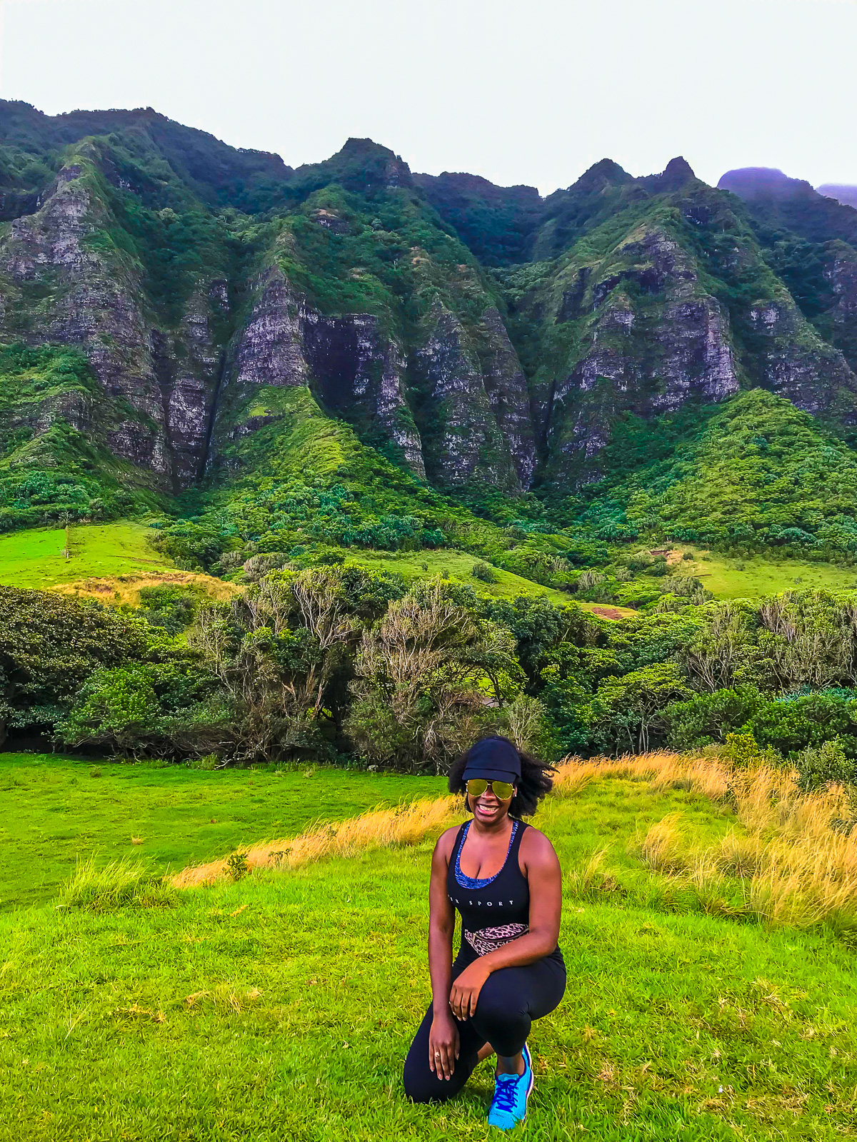 Jazzmine posing in front of vegetation-covered mountains at Oahu's Kualoa Ranch during a solo Raptor Adventure Tour excursion.