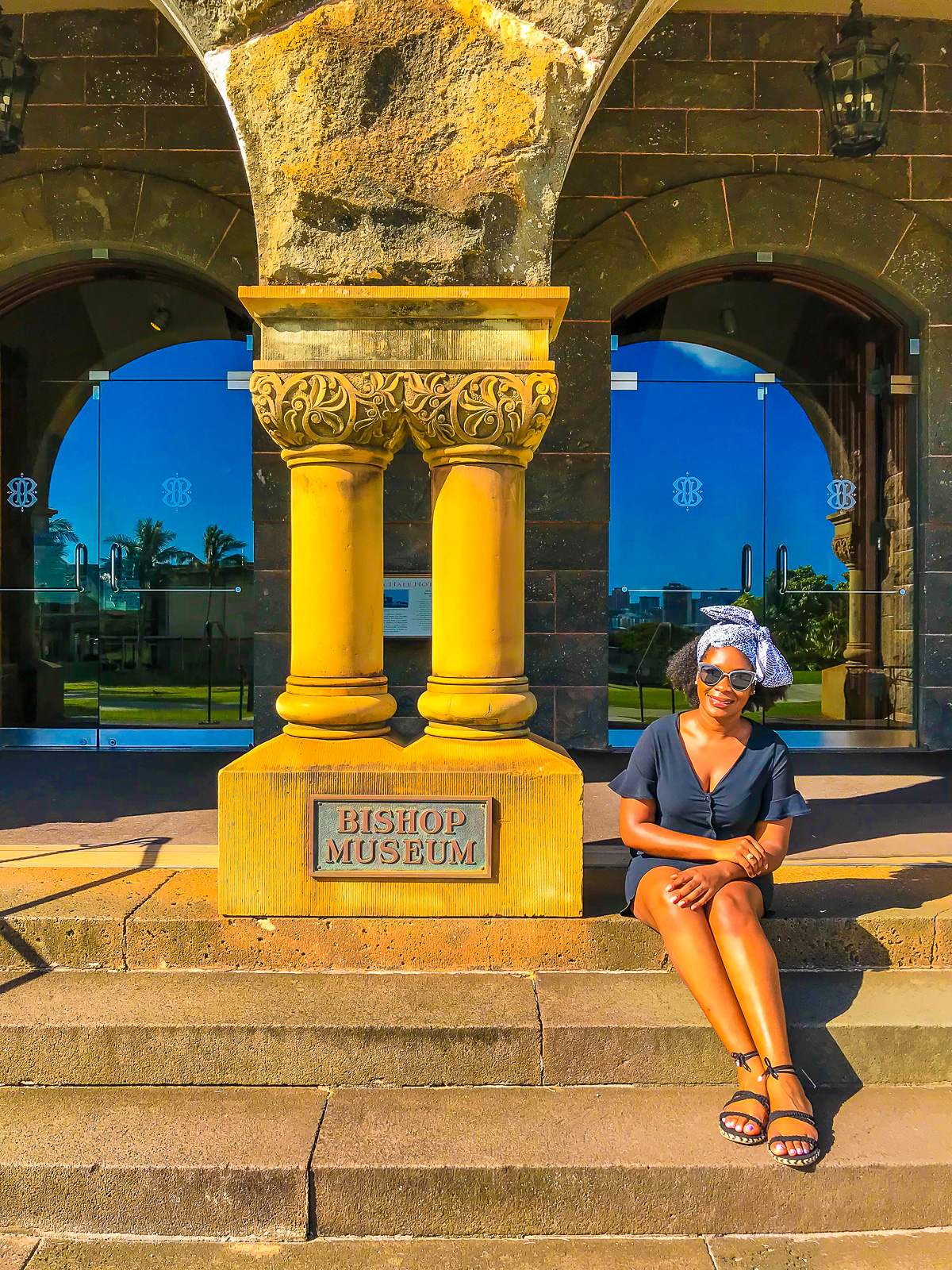Jazzmine seated on the stone steps in front of the Bishop Museum, Oahu, Hawai'i.
