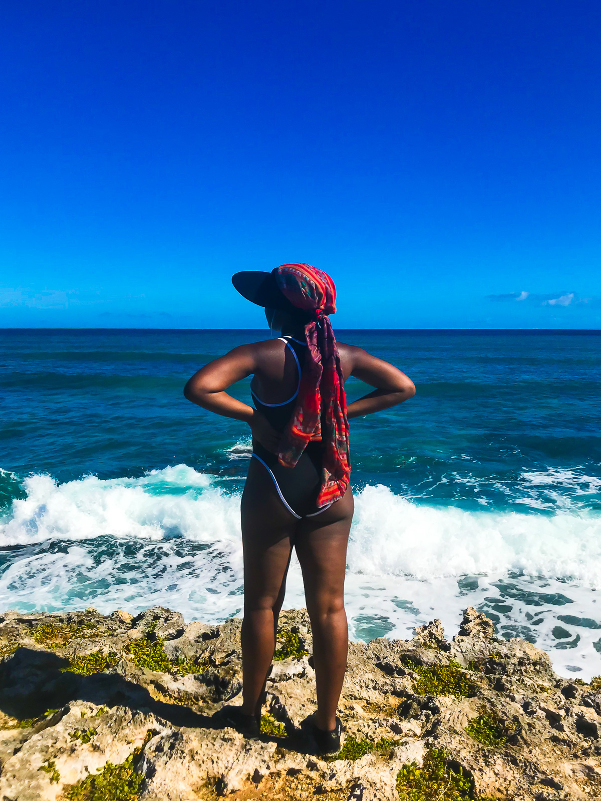 Black woman standing on Popoia Island off the coast of Kailua Beach, Oahu, looking out at the water.