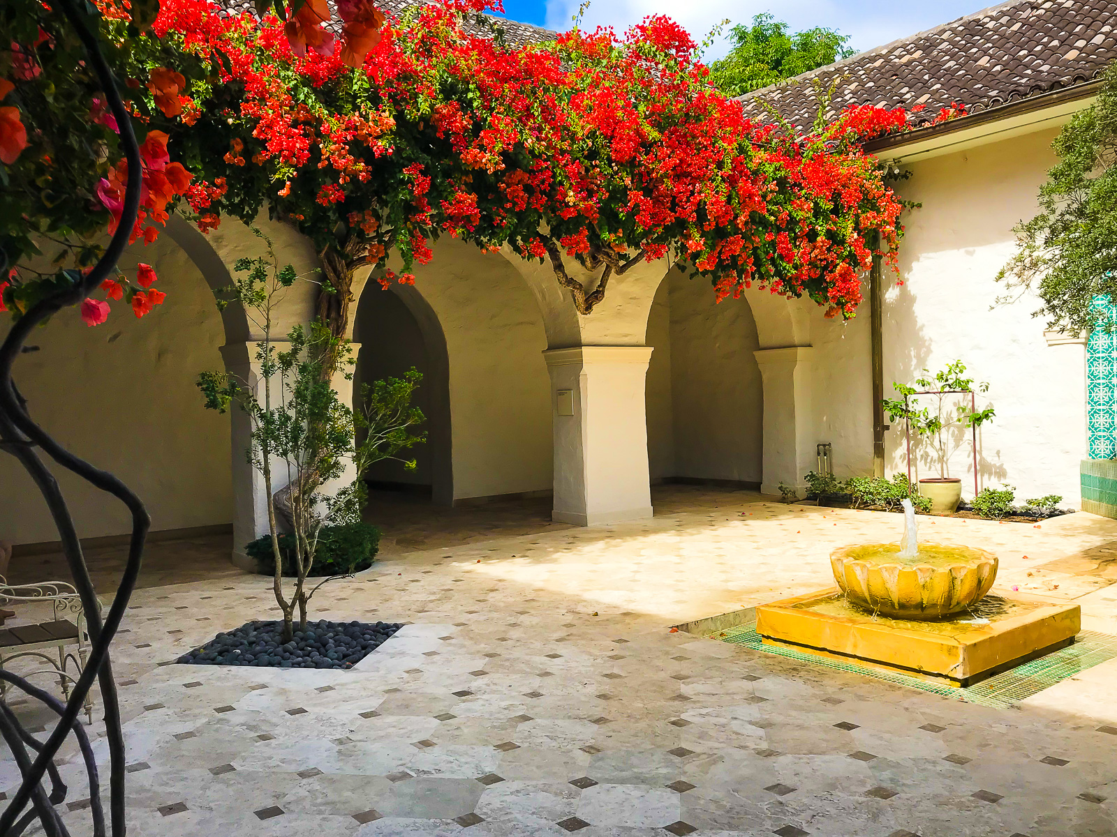 Courtyard at The Honolulu Museum of Art with tiled flooring a foutain, and flowering trees.