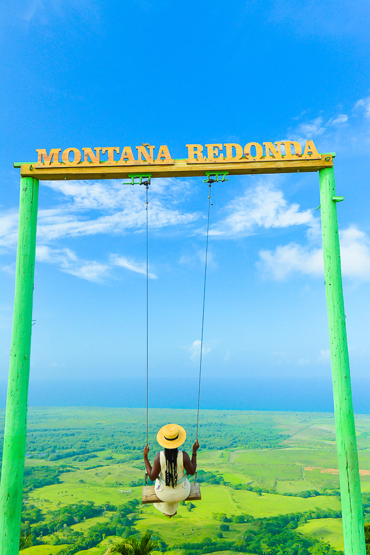Jazzmine swinging on the Punta Cana swing at DR's Montaña Redonda, wearing a straw boater hat and cream colored crochet dress.
