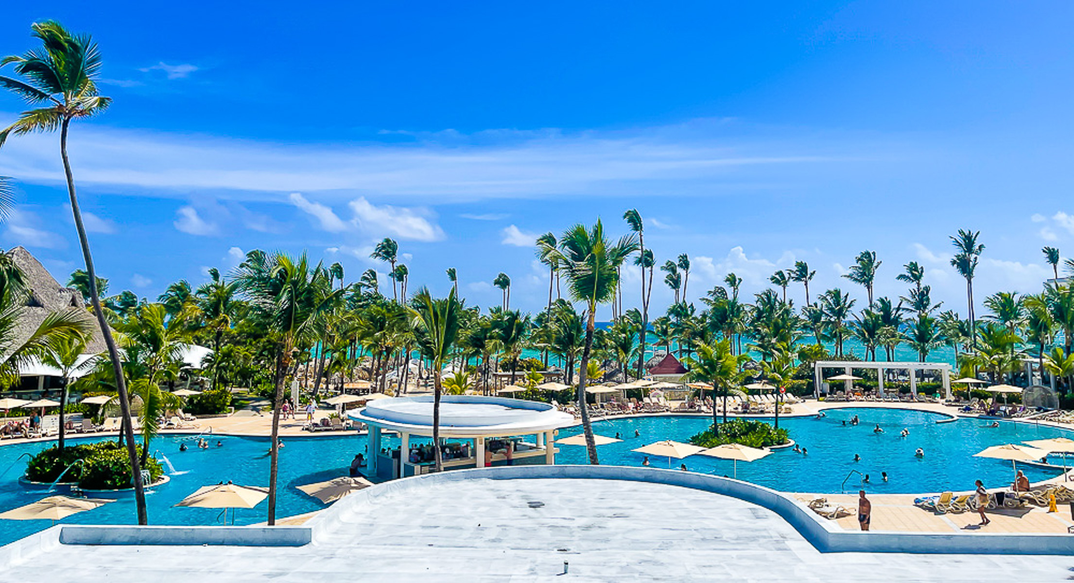Punta Cana resort pool with palm trees blowing the wind.