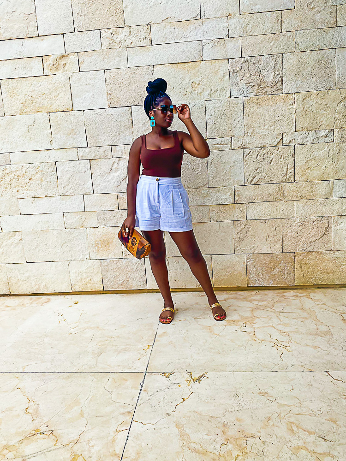 Jazzmine standing in front a Cozumel beach resort wearing white linen shorts and a brown square-neck tank top.