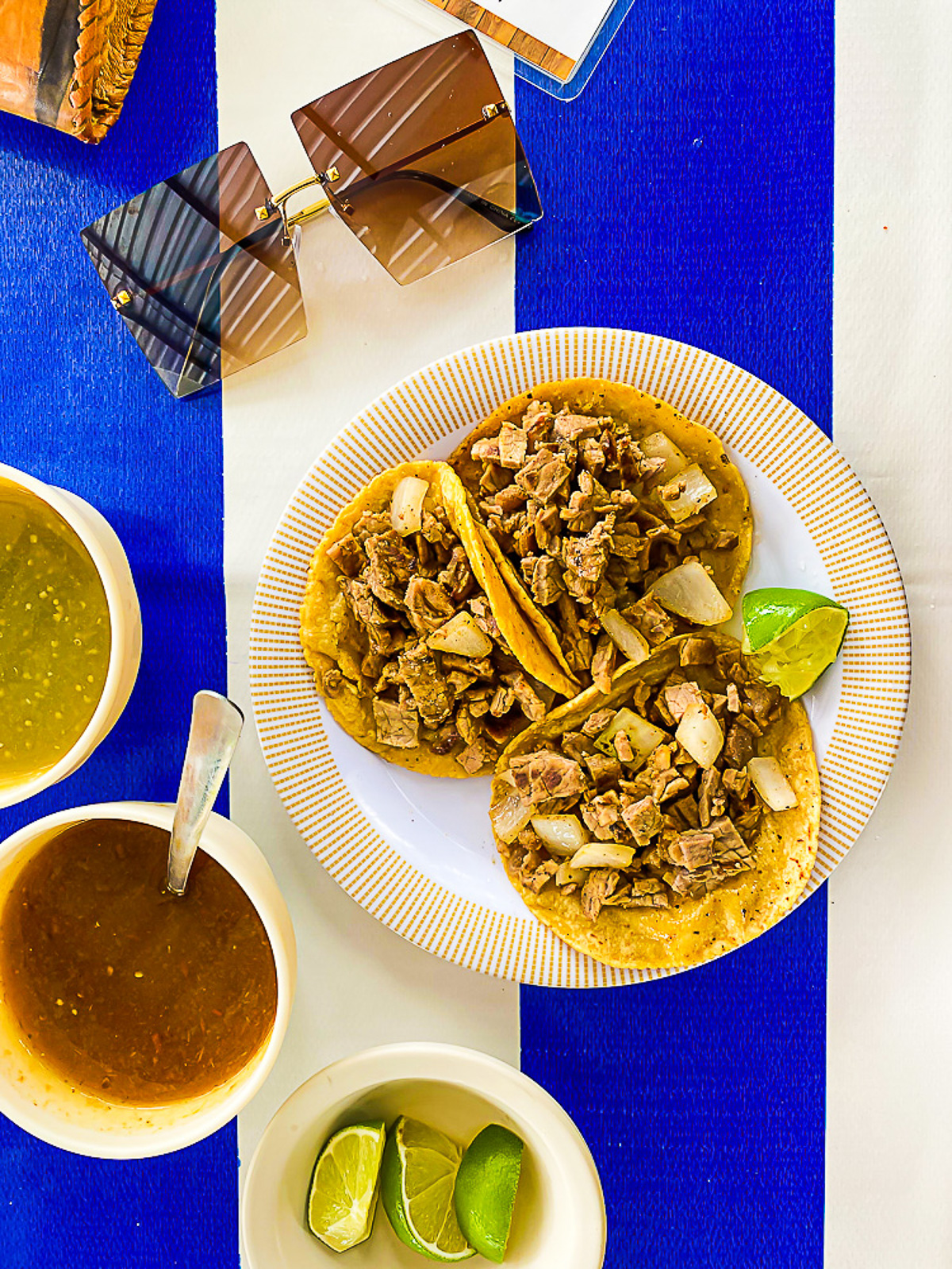 plate of beef tacos with fresh limes and assorted salsas for lunch in Cozumel MX.