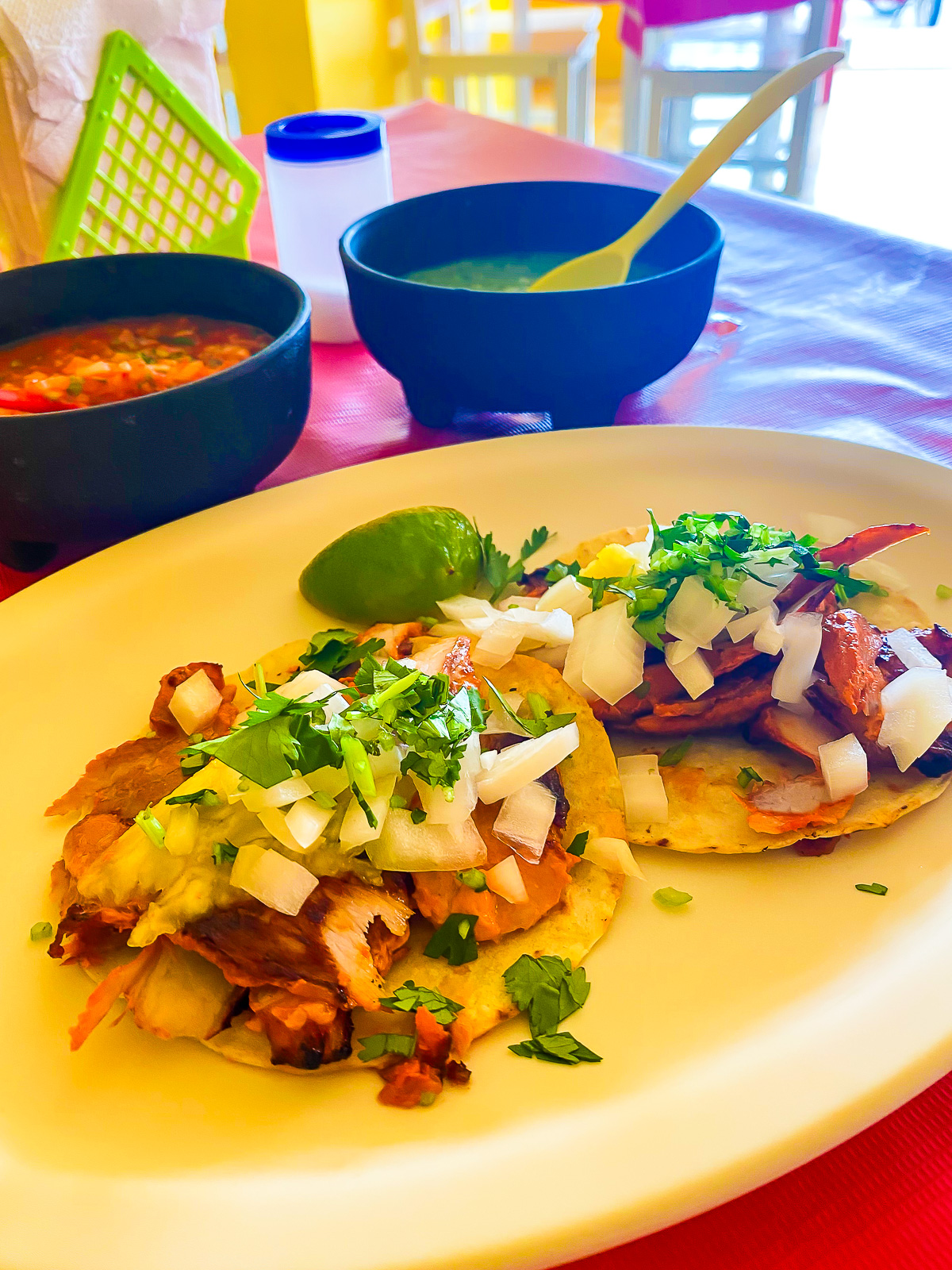 plate of authentic Mexican tacos al pastor with fresh limes and salsas at Los Sera's Taqueria Cozumel.