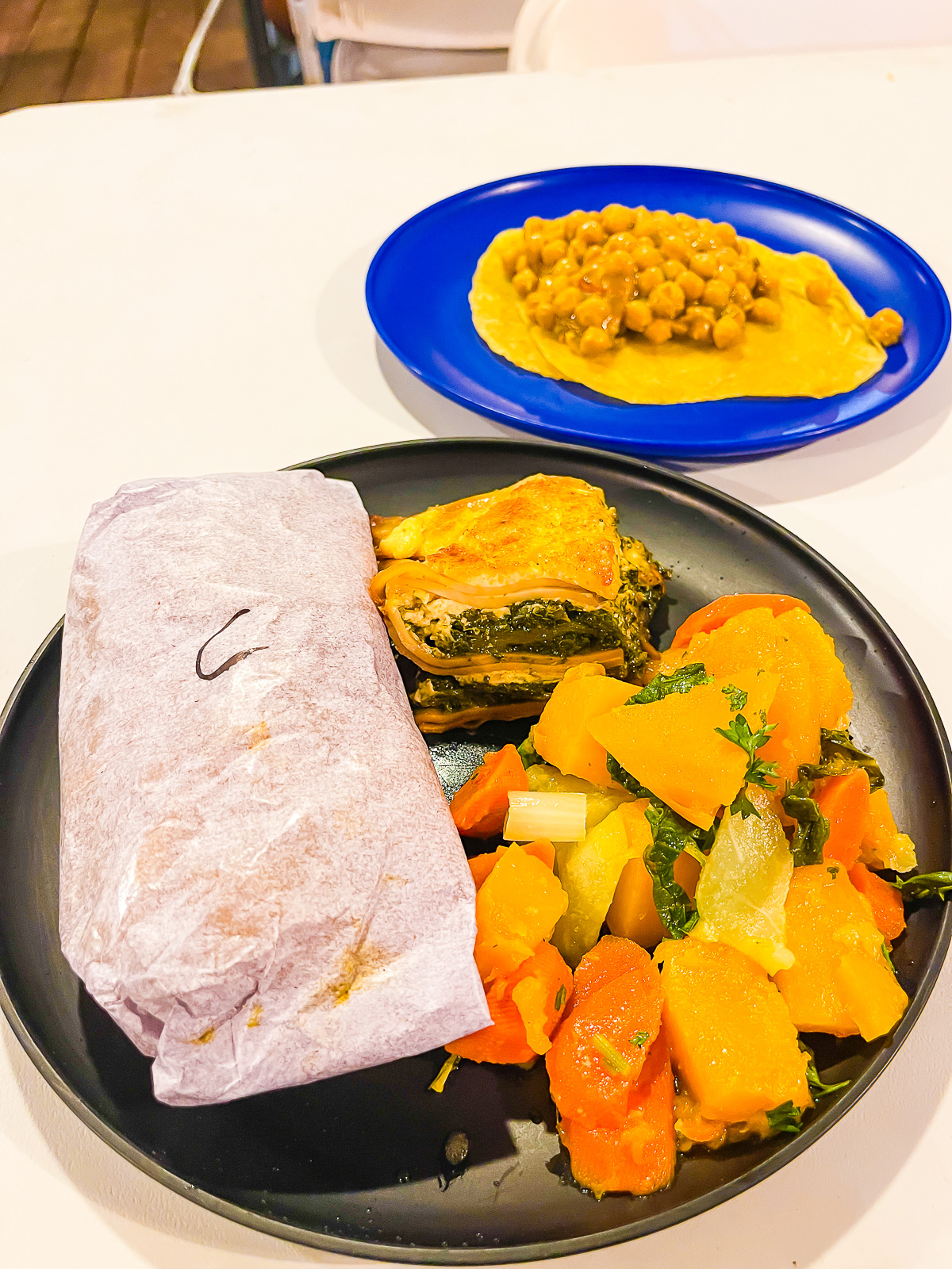 plates of Dodgy Dock Grenada street food with callaloo lasagna, mixed vegetables, chicken roti, and doubles with chickpeas.