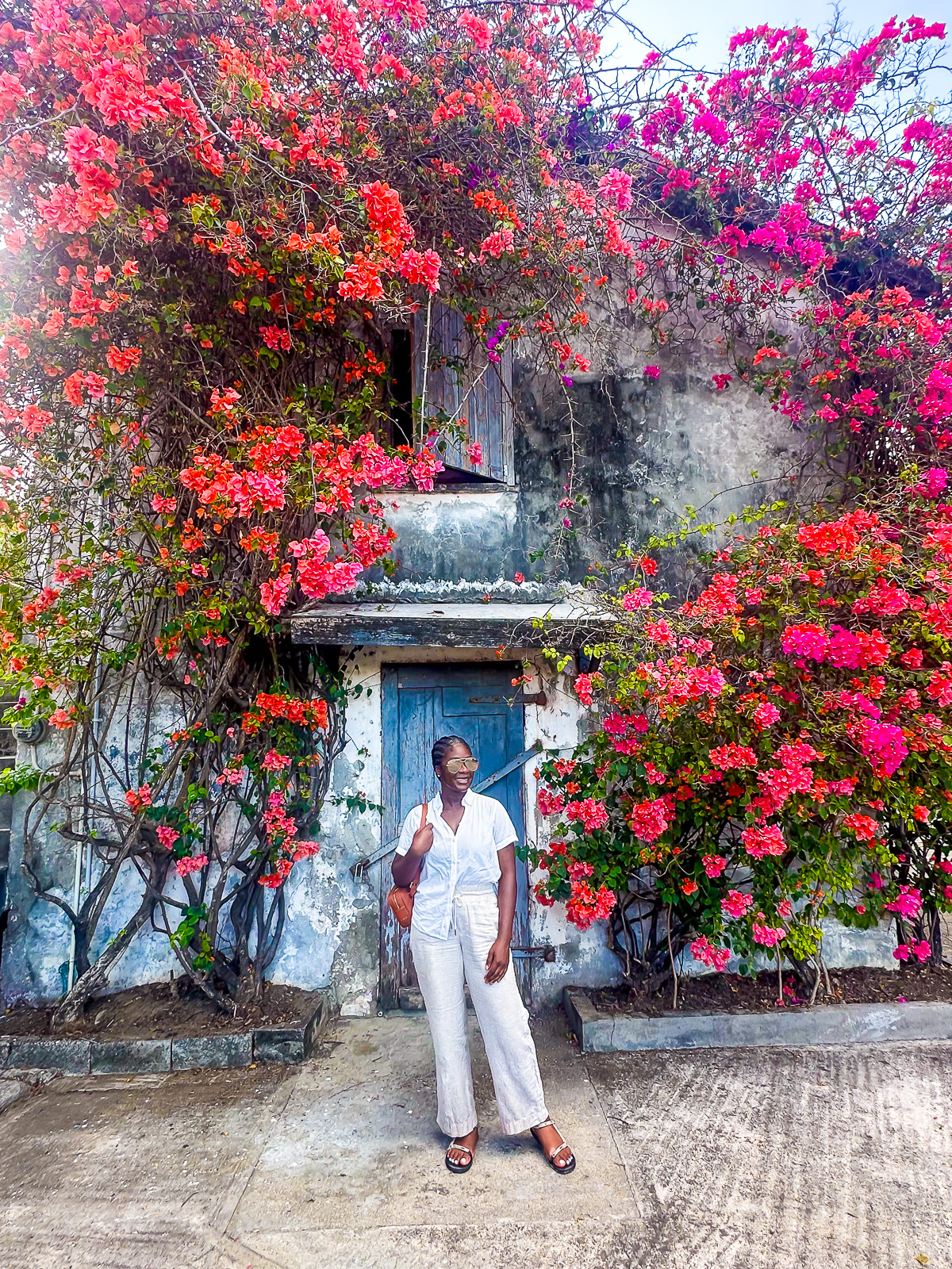Jazzmine standing in front of a building shrouded by bougainvillea at River Antoine Rum Estate in Grenada.