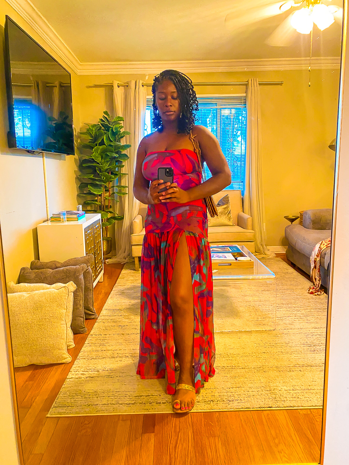 Jazzmine taking a selfie in a gold framed full-body mirror wearing a tropical printed hot pink maxi dress with a high slit.