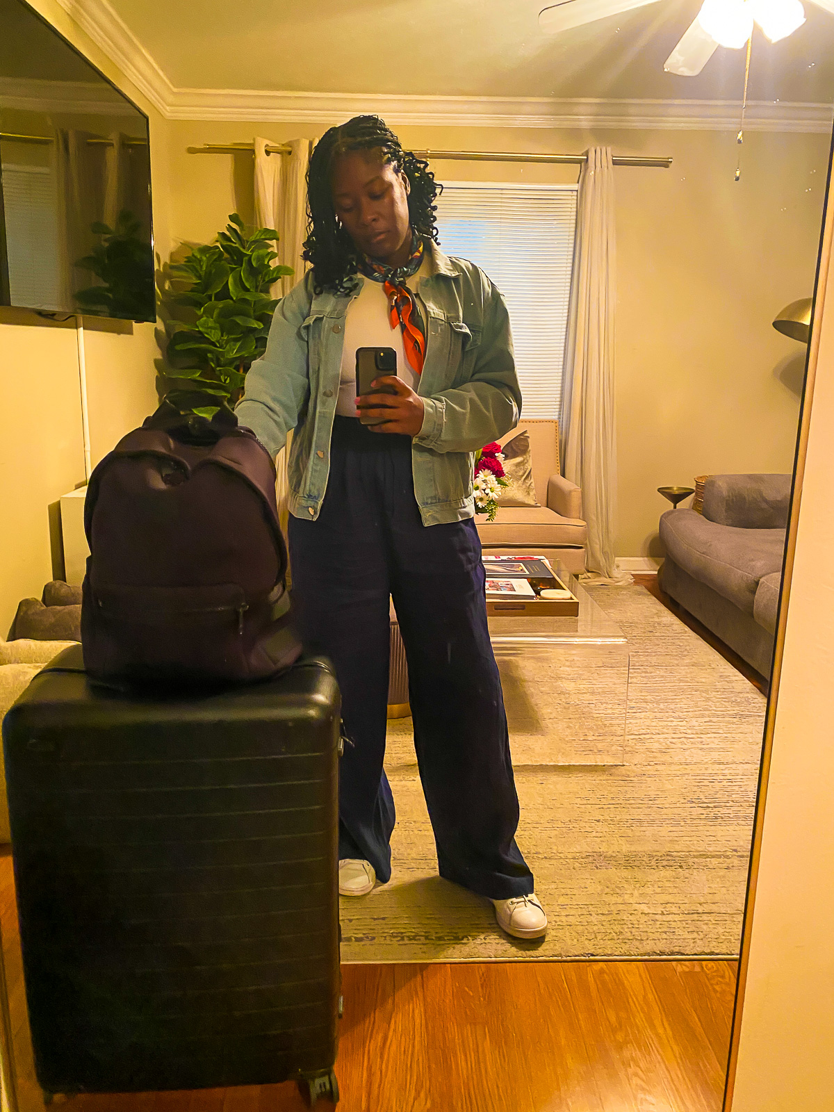 Jazzmine taking a mirror selfie with luggage packed with vacation clothes to wear in Costa Rica.